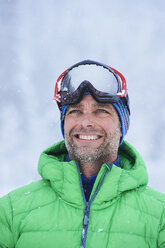 Porträt eines glücklichen reifen Mannes im fallenden Schnee, Gstaad, Schweiz - CUF04777