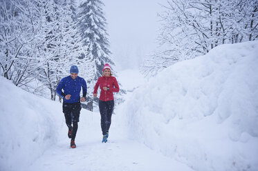 Female and male runners running in falling snow, Gstaad, Switzerland - CUF04789