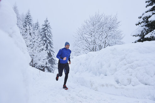 Männlicher Läufer, der im Tiefschnee auf der Bahn läuft, Gstaad, Schweiz - CUF04790