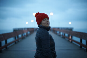 Porträt einer Frau auf einem Pier, die über die Schulter in die Kamera schaut - CUF04821