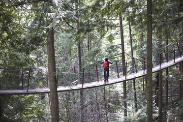 Frau geht über die Capilano-Hängebrücke, Rückansicht, Vancouver, Kanada - CUF04824