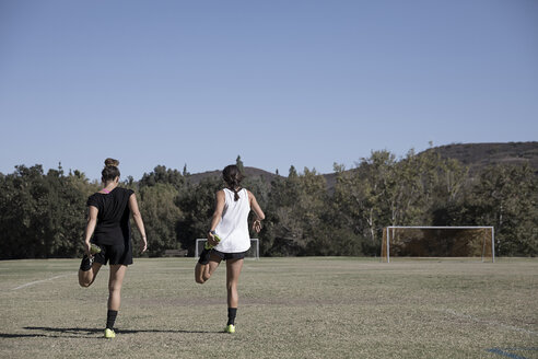 Women on football pitch warming up, stretching legs - ISF01134