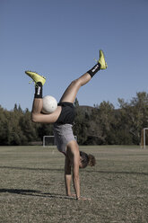 Frauen auf dem Fußballplatz machen Handstand mit dem Fußball - ISF01147