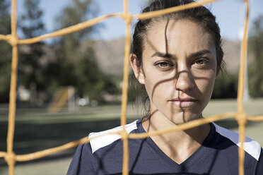 Portrait of woman behind football goal netting looking at camera - ISF01162