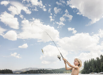 Portrait of shirtless boy standing with fishing rod in forest stock photo