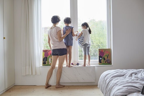 Mutter, Sohn und Tochter schauen aus dem Schlafzimmerfenster, Rückansicht - ISF01259