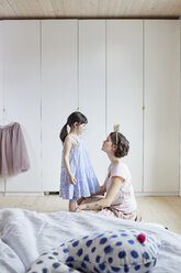 Mother and daughter in bedroom, face to face, mother wearing crown headband - ISF01262