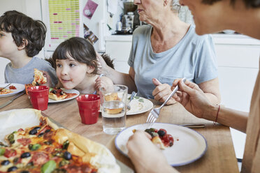 Familie in der dritten Generation sitzt am Küchentisch und isst Pizza - ISF01267