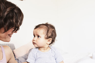 Mother sitting face to face with baby daughter, baby daughter with sad expression - ISF01268