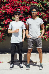 Friends standing next to each other beside red bougainvilleas - ISF01292