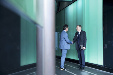 Geschäftsleute beim Händeschütteln in einem modernen Glasgebäude, London, UK, lizenzfreies Stockfoto