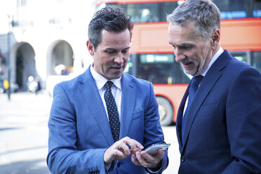 Businessmen in street looking at smartphone, London, UK - CUF04914