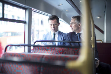 Two businessmen looking at smartphone on double decker bus - CUF04934