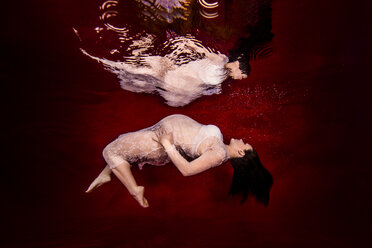 Schwangere Frau, die sich nach hinten beugt, drapiert in durchsichtigem Spitzenstoff, Spiegelung auf der Wasseroberfläche, Unterwasseransicht - CUF04937