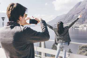 Man photographing girlfriend at lakeside, Monte San Primo, Italy - CUF04957