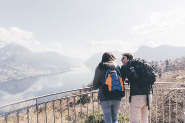 Couple looking out over mountain lakeside, Monte San Primo, Italy - CUF04964