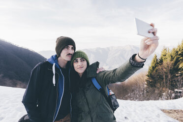 Hiking couple taking selfie in snowy mountains, Monte San Primo, Italy - CUF04982