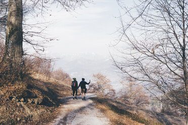 Rear view of hiking couple hiking along rural road, Monte San Primo, Italy - CUF04983