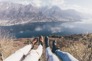Legs of couple over mountain lakeside, Monte San Primo, Italy - CUF04984
