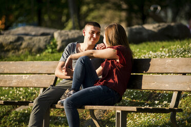 Paar sitzt auf einer Parkbank, von Angesicht zu Angesicht, lächelnd - CUF05009