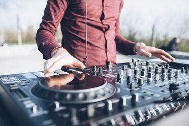 Young man using mixing desk at roof party, mid section, close-up - CUF05025