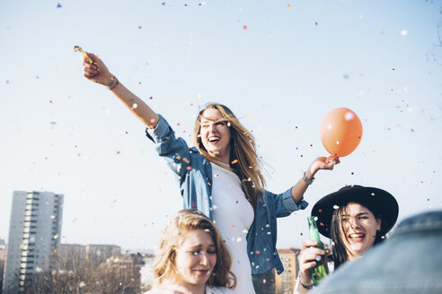 Group of friends enjoying roof party, confetti in air - CUF05039