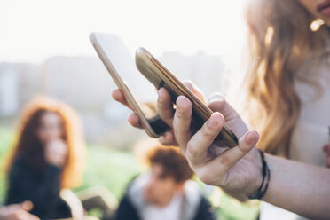 Two young women outdoors, looking at smartphones, mid section, close-up - CUF05041