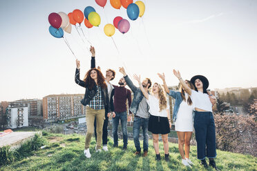 Portrait of group of friends, standing on roof, holding helium balloons - CUF05050