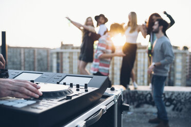 Group of friends enjoying roof party, young man using mixing desk - CUF05055