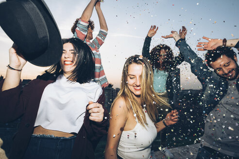 Group of friends dancing, enjoying roof party, confetti in air - CUF05063
