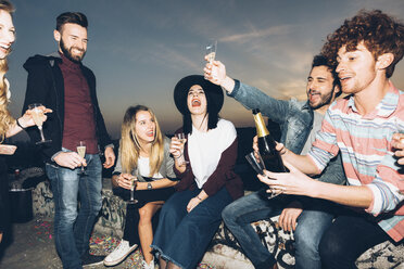 Group of friends enjoying roof party, holding champagne glasses, making a toast - CUF05067