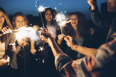 Eine Gruppe von Freunden genießt eine Dachparty mit Wunderkerzen in der Hand - CUF05074