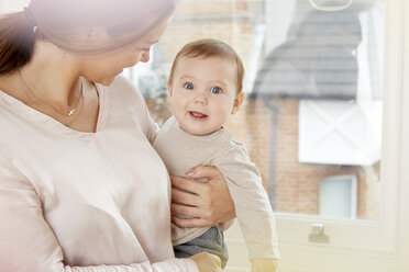 Portrait of baby boy being carried by mother at home - CUF05083