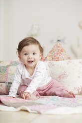 Portrait of baby girl, sitting on blanket, laughing - CUF05100