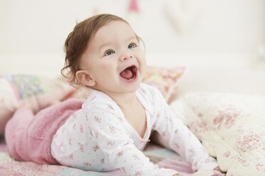 Portrait of baby girl, lying on her front, laughing - CUF05101