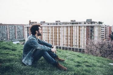 Young man sitting on rooftop garden, looking at view - CUF05117