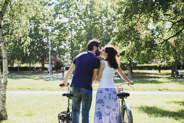 Rückansicht eines Paares mit Fahrrädern, das sich im Park küsst, Arezzo, Toskana, Italien - CUF05142