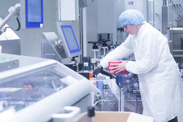Worker retrieving packaged products from production line in pharmaceutical plant - CUF05215