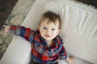 Porträt eines männlichen Kleinkindes, das auf dem Sofa liegt und nach oben schaut - CUF05239