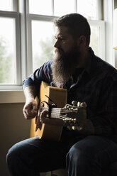 Mann spielt Gitarre neben dem Fenster - CUF05285