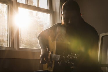 Mann spielt Gitarre neben dem Fenster - CUF05289