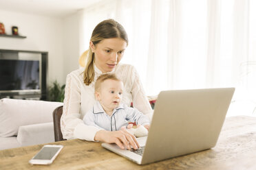 Mother working and caring for baby at home - CUF05317