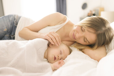 Mother watching over sleeping baby on bed - CUF05324