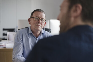 Male colleagues in discussion at office desk - CUF05332