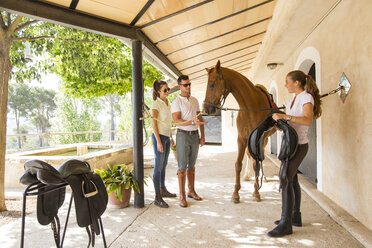 Pferdepflegerin trägt Sattel für Pferd in ländlichem Stall - CUF05415