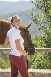 Porträt einer jungen Pferdepflegerin mit Pferd in einem ländlichen Stall - CUF05417