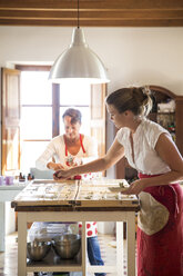 Junge Frau, die in einer Werkstatt für handgemachte Seife getrockneten Lavendel auf Seifenstücke aufträgt - CUF05435