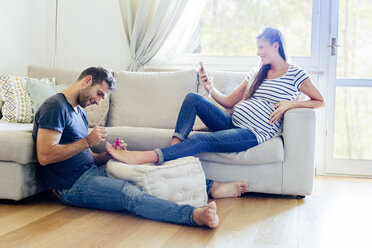 Man pampering pregnant woman on sofa - CUF05458