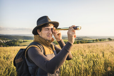 Mittlerer erwachsener Mann, stehend im Feld, durch Fernrohr blickend, Neulingen, Baden-Württemberg, Deutschland - CUF05470