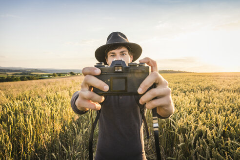 Mittlerer erwachsener Mann, stehend im Feld, macht ein Selfie mit Spiegelreflexkamera, Neulingen, Baden-Württemberg, Deutschland - CUF05473